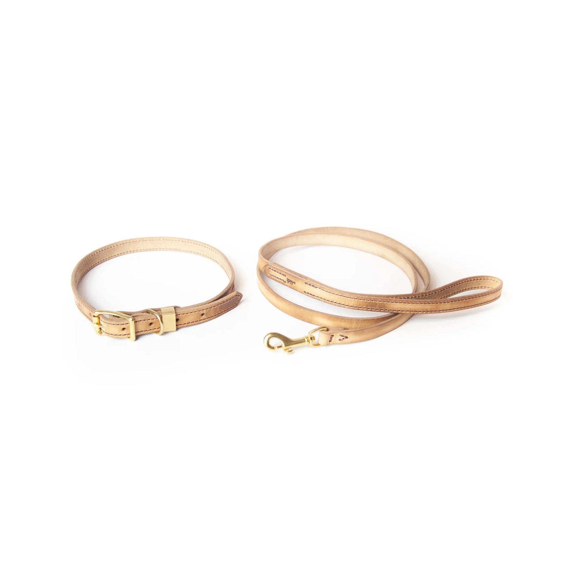 Two beige leather dog collars and leashes on a white background