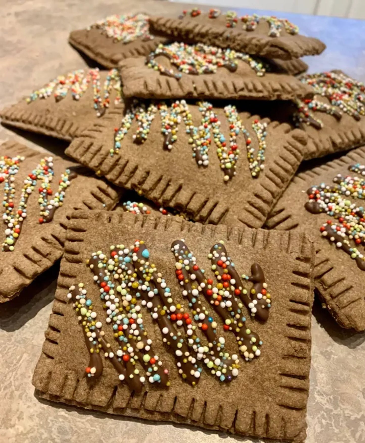 Brown cookies with colorful sprinkles on a stone surface