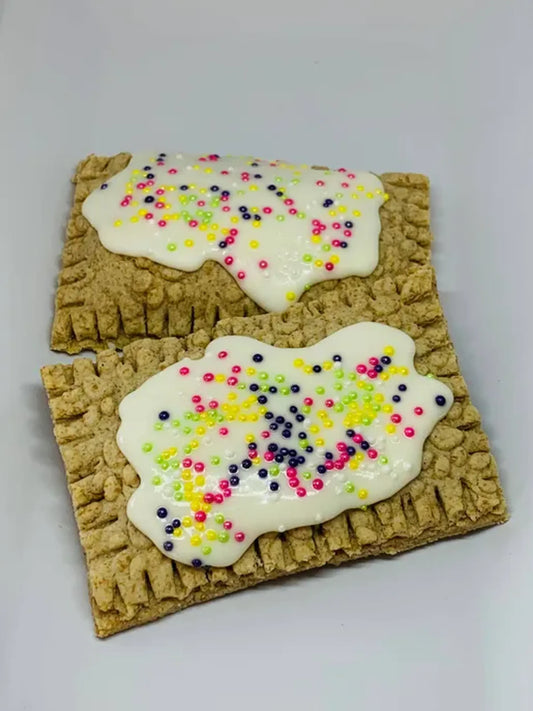 Two rectangular cookies with white icing and colorful sprinkles on a light gray background