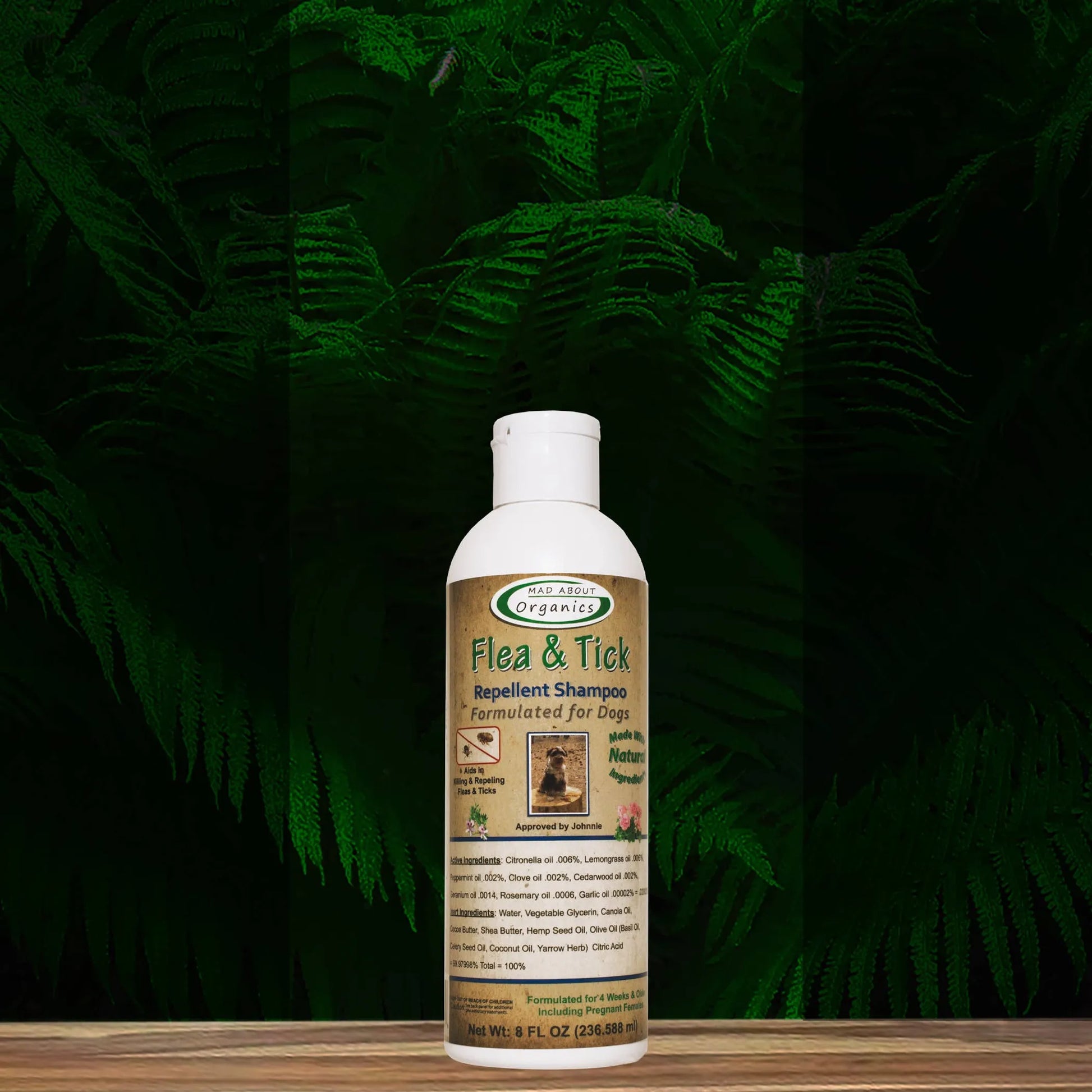 Flea and tick repellant shampoo bottle on a wooden surface with green foliage in the background