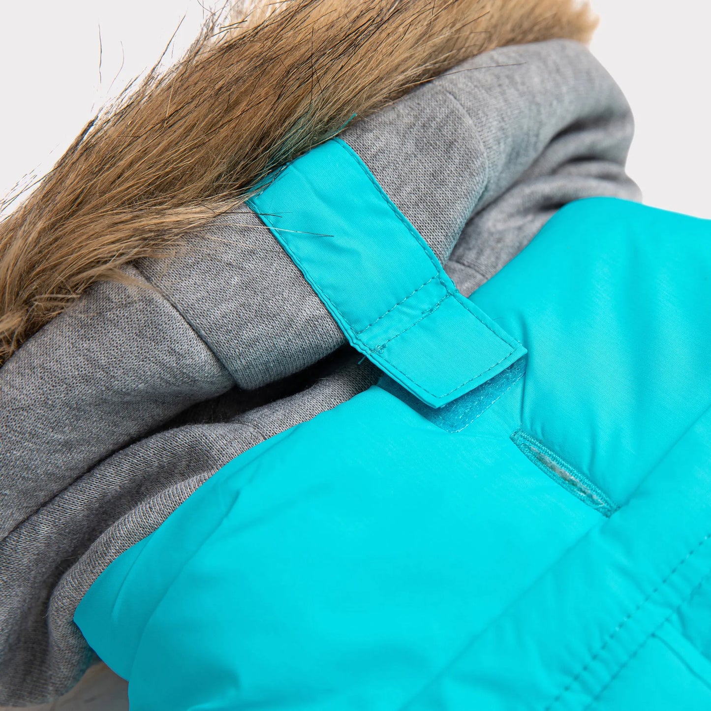 Close-up of a teal jacket with gray hood and fur lining on a white background