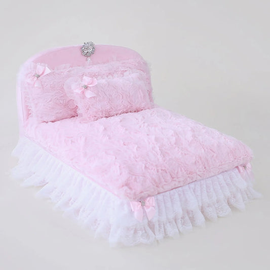Pink pet bed with fringes and decorative elements on a light gray background