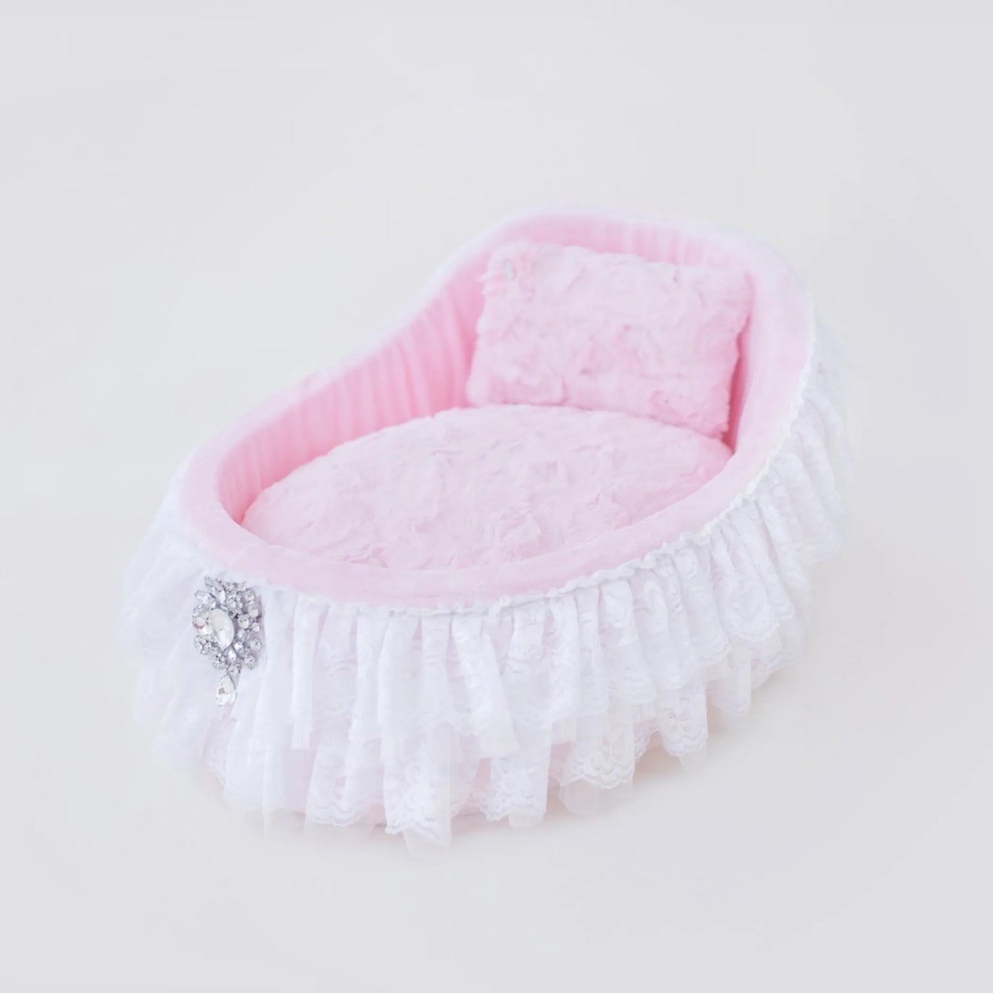 Pink pet bed with white lace trim on a light background