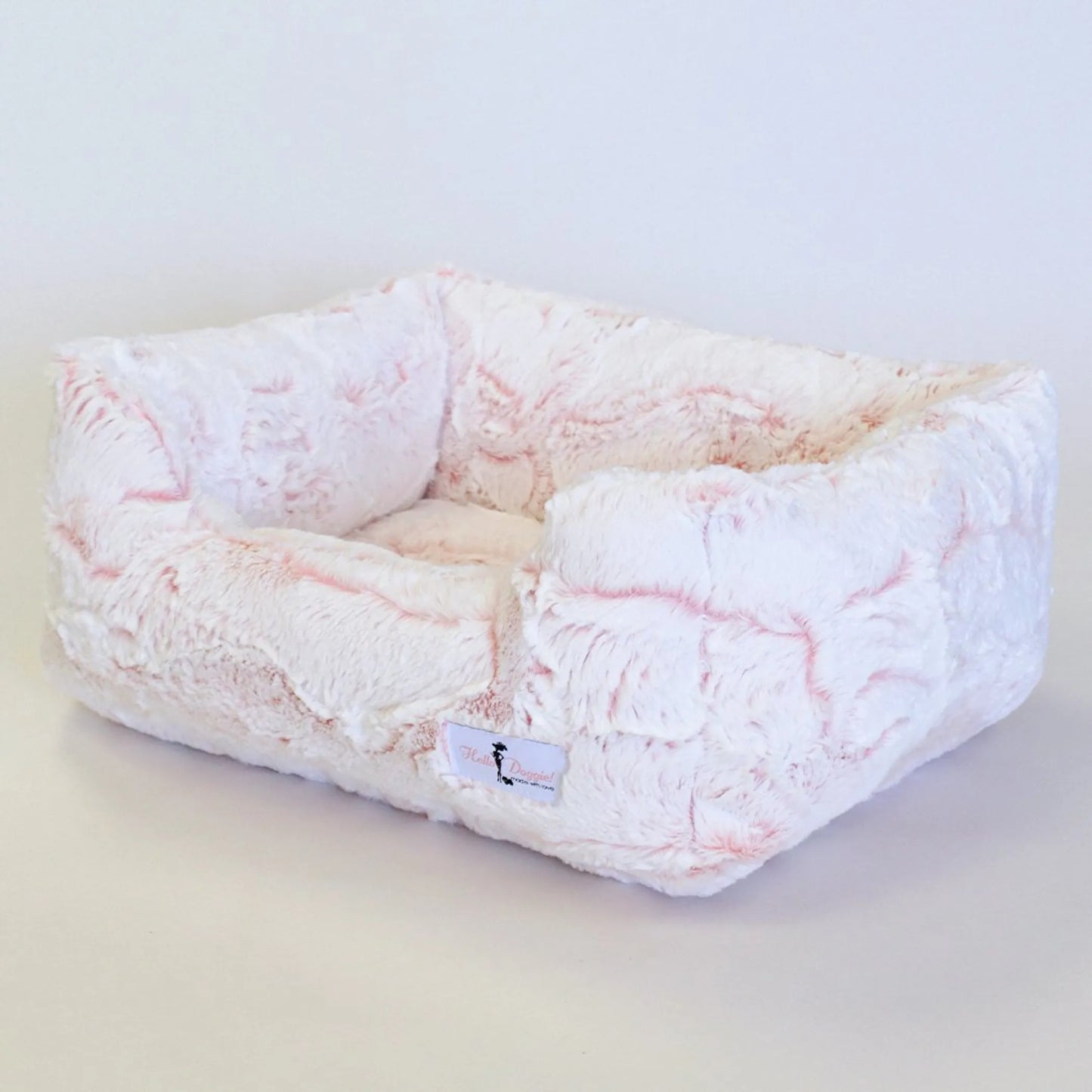 Fluffy pet bed with pink and white pattern on a light background