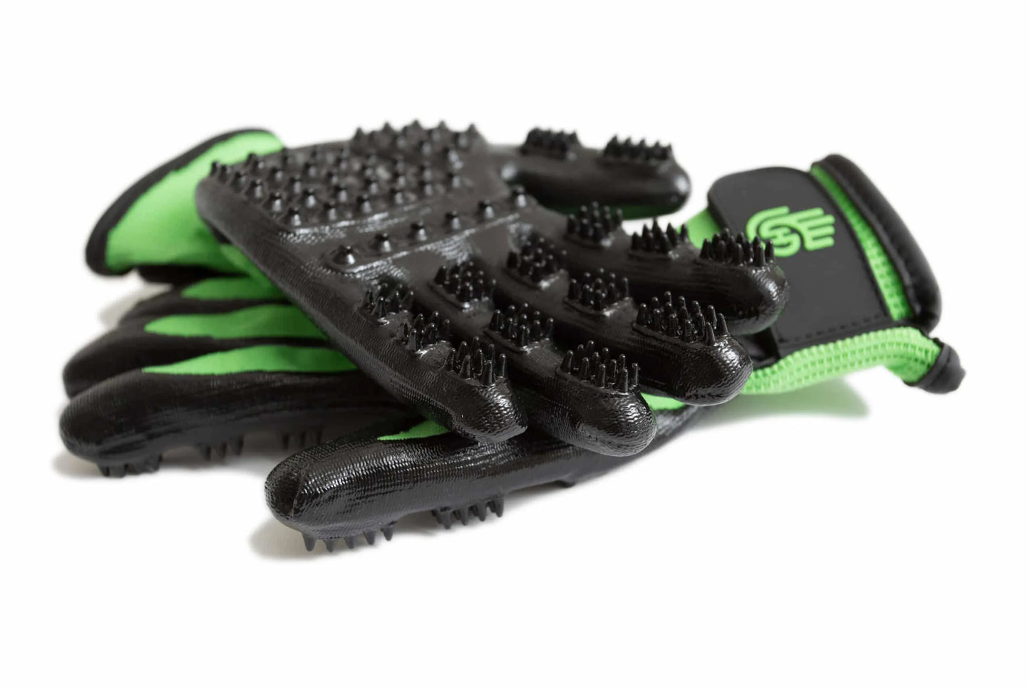 Pair of black grooming gloves with green accents on a white background