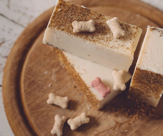 Block of white soap with dog bone-shaped bath bombs on a wooden surface